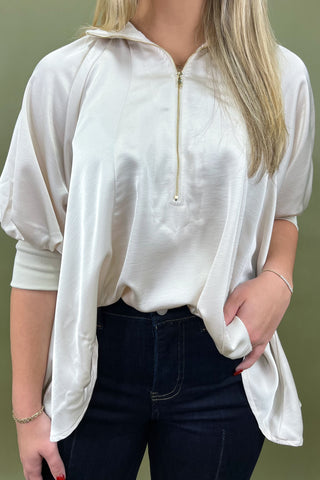 Person wearing a white zip-up shirt with a green background