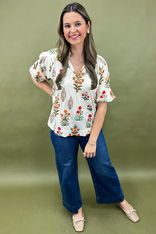 Woman wearing a floral blouse and blue jeans on a green background
