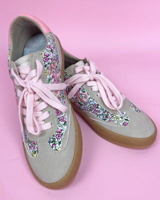 Floral-patterned sneakers with pink laces on a pink background