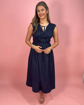 Woman wearing a navy blue dress against a pink background