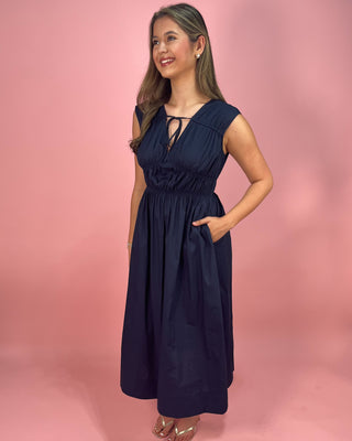 Woman wearing a navy blue dress against a pink background