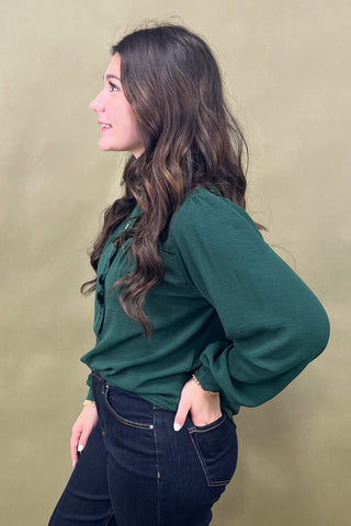 Woman wearing a green blouse against a beige background