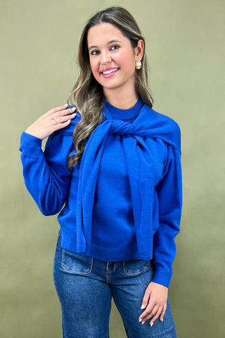 Woman wearing a blue sweater with a large bow tie against a green background