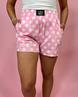 Pink polka dot shorts with 'Lulu Mac' waistband on a pink background