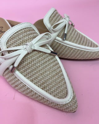Beige loafers with white laces on a pink background