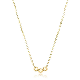 Gold necklace with three round pendants on a white background