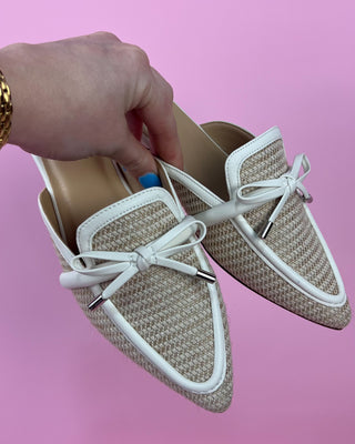 Beige loafers with white laces on a pink background