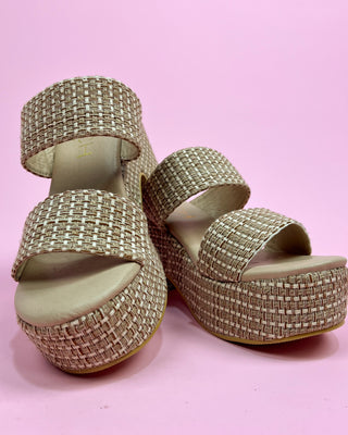 Gold embellished sandals on a pink background