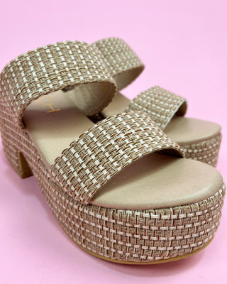 Gold woven sandal on a pink background
