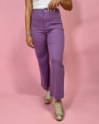 Person wearing purple pants on a pink background
