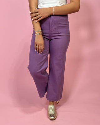 Person wearing purple pants on a pink background