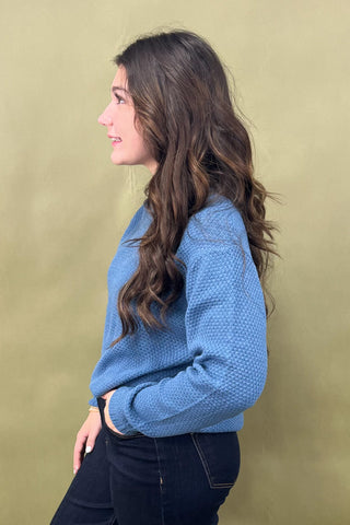 Woman wearing a blue sweater against a green background