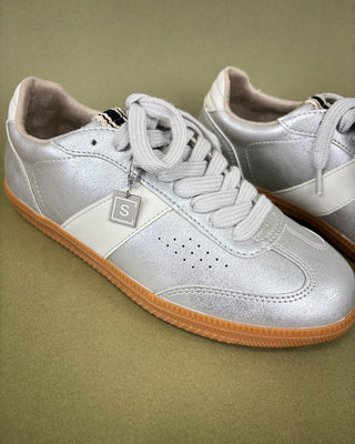 Silver sneakers with brown soles on a green background