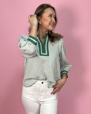 Woman wearing a green and white striped blouse with a pink background