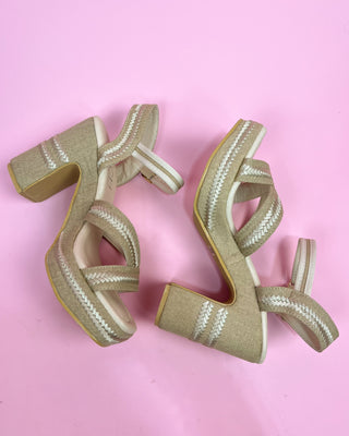 Pair of beige high-heeled sandals on a pink background