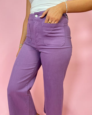 Purple pants worn by a person on a pink background