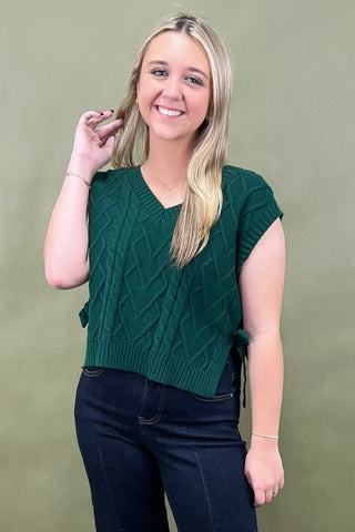 Woman wearing a green knitted top against a plain background