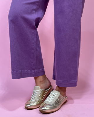 Purple pants and gold sneakers on a pink background