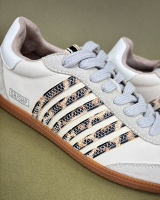 White sneaker with decorative elements on a green background