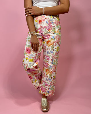 Person wearing colorful floral pants on a pink background