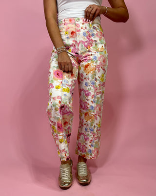 Person wearing floral pants on a pink background