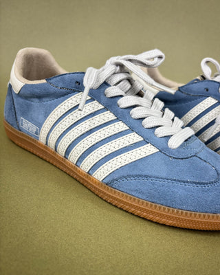 Blue sneaker with white stripes on a green background