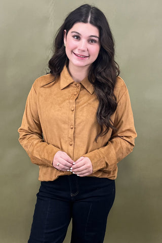 Woman wearing a mustard yellow shirt against a green background