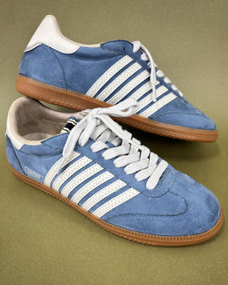 Pair of blue sneakers with white stripes on a green background