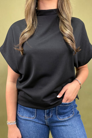 Person wearing a black t-shirt and blue jeans against a green background