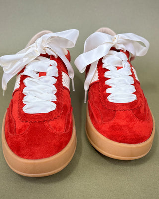Red sneakers with white laces on a beige background