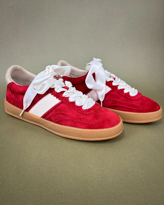 Red sneakers with white floral lace on a beige background
