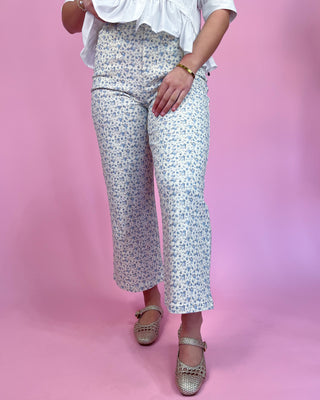 Person wearing white floral pants on a pink background