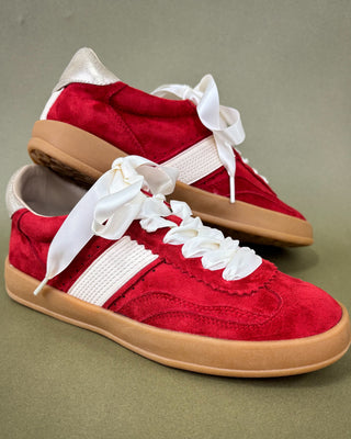 Red sneakers with white laces on a green background