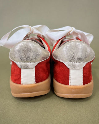 Red and white sneakers with silver soles on a green background