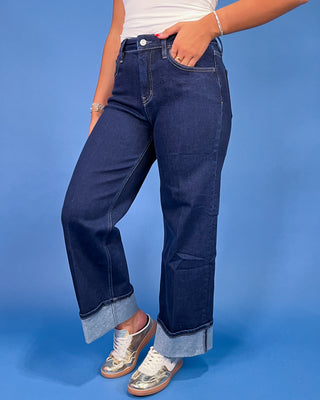 Dark wash cuffed straight leg jeans with a high-rise waist and wide rolled hems, shown on model.