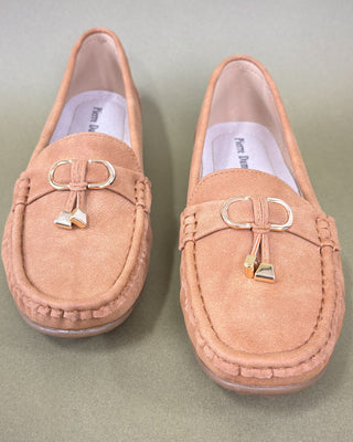 Pair of tan loafers with decorative buckles on a light green background
