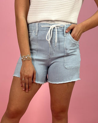 Person wearing blue striped shorts on a pink background