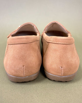 Pair of tan loafers on a light green background
