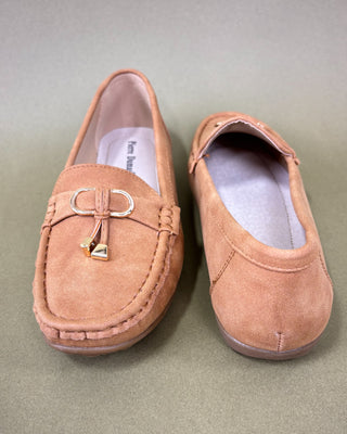 Pair of tan loafers with a decorative buckle on a light green background