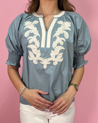 Blue blouse with white embroidery on a pink background