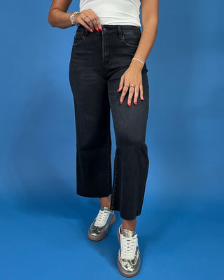 Black cropped wide leg jeans with a high-rise waist and raw hem, shown on model.
