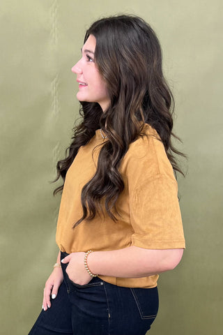 Woman wearing a mustard yellow shirt against a green background