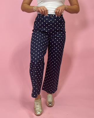 Person wearing navy pants with white polka dots on a pink background