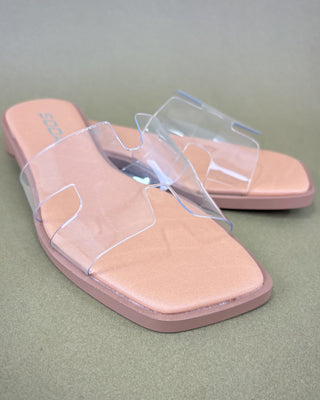 Pair of pink sandals with clear straps on a green background