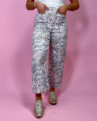 Person wearing floral pants on a pink background