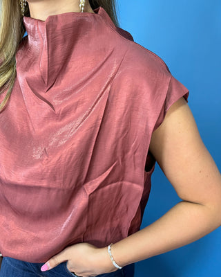 Rust satin sleeveless top with draped mock neckline, structured shoulders, and relaxed fit.