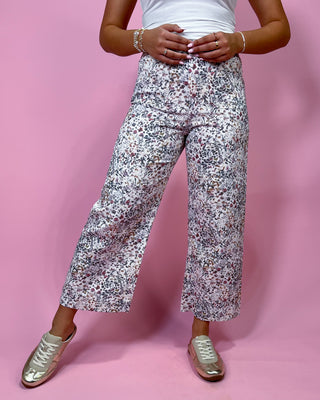 Person wearing floral pants on a pink background