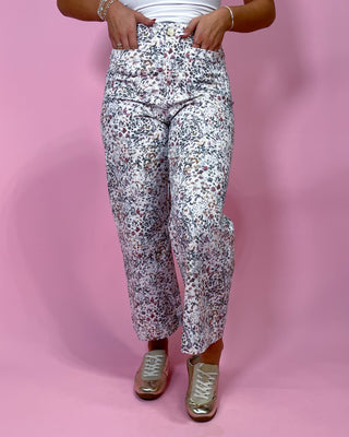 Person wearing floral pants on a pink background