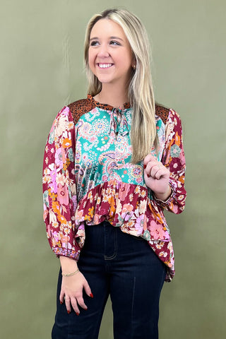 Woman wearing a colorful patterned blouse against a green background