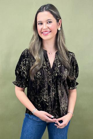Woman wearing a black sequin top and blue jeans against a green background